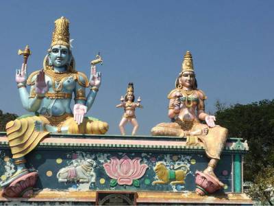"Colorful statues of Lord Shiva, Goddess Parvati, and Lord Kartikeya adorning the temple entrance, featuring detailed South Indian artistry and vibrant designs