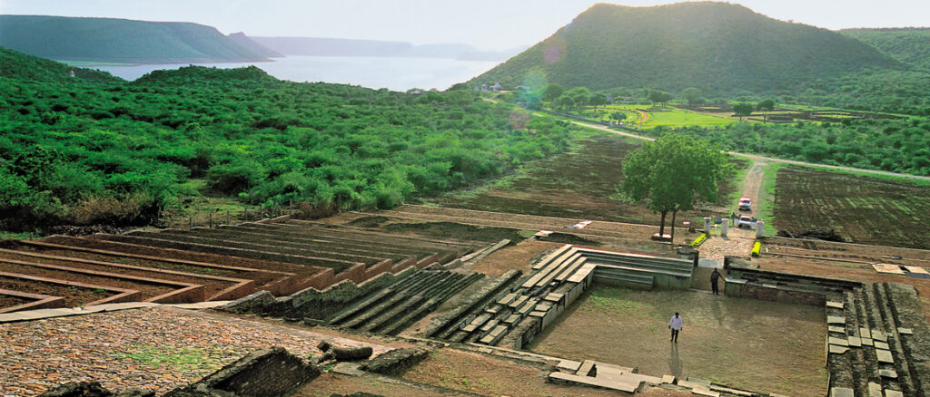 Panoramic view of Nagarjunakonda Buddhist excavation site surrounded by lush greenery, ancient stone structures, and the Nagarjunasagar reservoir in the background near Nagarjunasagar Dam & Ethipothala Waterfalls