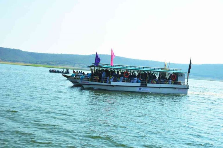 Tourist ferry boat carrying visitors across the Somasila Reservoir, with colorful flags and scenic hills in the background, offering boating and nature experiences in Telangana at Somasila Reservoir and Temple