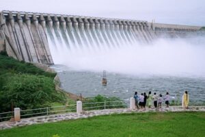 Tourists watching water gushing from Nagarjunasagar Dam spillway gates, surrounded by lush greenery and mist, one of India’s largest dams on the Krishna River