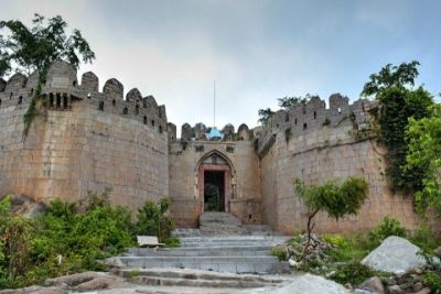 Historic view of Devarakonda Fort with ancient stone walls, arched entrance, and surrounding greenery, a heritage monument and tourist attraction near Nalgonda, Telangana