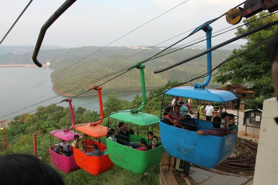 Colorful ropeway cabins carrying tourists down to Pathala Ganga at Srisailam, offering scenic views of the Krishna River, forested hills, and the reservoir