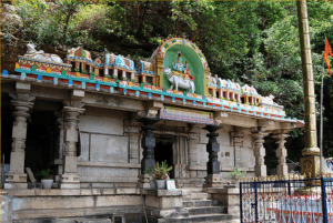 The entrance to the Uma Maheshwaram Temple, situated in the Nallamala Hills near Achampet, features traditional South Indian architecture, vibrant deity carvings, and lush greenery in the background.